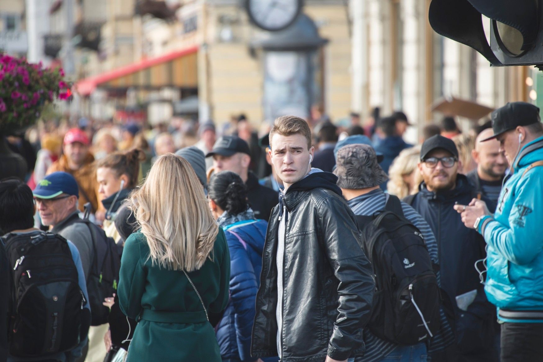 En ung man ser sig runt i en folkmassa. Kanske han söker efter jobb. 